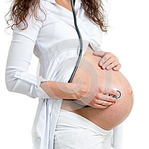 Pregnant woman using stethoscope to hear babies