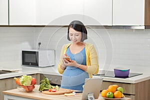 Pregnant woman using a tablet computer in her kitchen