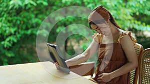 Pregnant woman using tablet in garden
