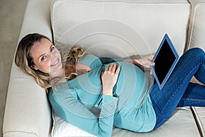Pregnant woman using tablet lying on the couch