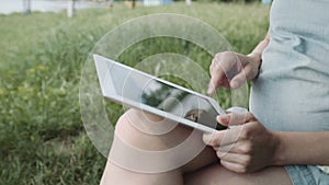 Pregnant woman using tablet pc in park