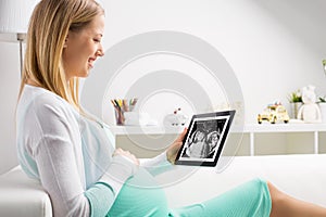Pregnant woman using tablet to look at sonography results
