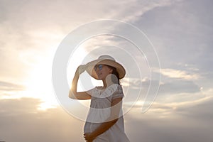 Pregnant woman walking on the beach at sunset