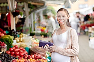Pregnant woman with wallet buying food at market