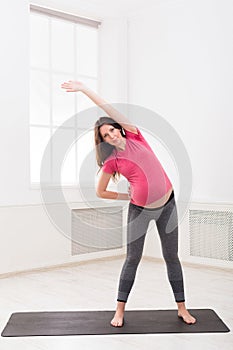 Pregnant woman warmup stretching training indoors