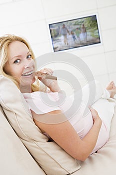 Pregnant woman watching television and eating choc