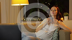 Pregnant woman watching tv and drinking tea