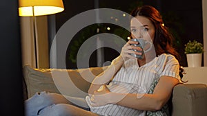 Pregnant woman watching tv and drinking tea