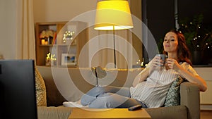 Pregnant woman watching tv and drinking tea
