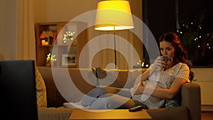 Pregnant woman watching tv and drinking tea