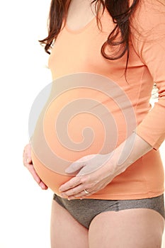 Pregnant woman wearing orange shirt touching her belly