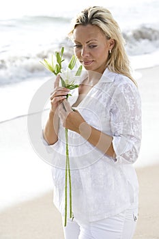 Pregnant woman wearing white on beach with flower