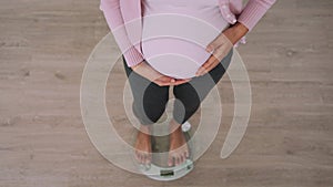 Pregnant woman is weighing to check for weight gain during pregnancy. woman touch stomach to express concern for her baby. signs o