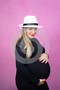 Pregnant woman in white hat holding barria with her hands