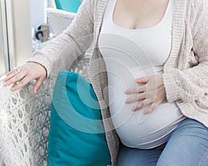 Pregnant woman in white shirt holding hand on her belly