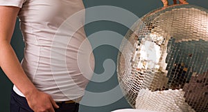 Pregnant woman in a white shirt standing in front of a disco ball