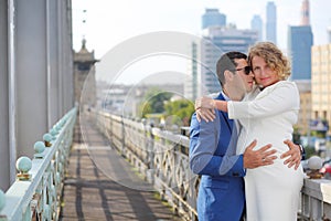 Pregnant woman in white and stylish man embrace photo