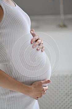 Pregnant woman in white sweater holding her belly.  close up of happy pregnant