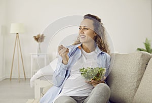 Pregnant woman who eats many different vegetables during pregnancy enjoys fresh green salad at home.