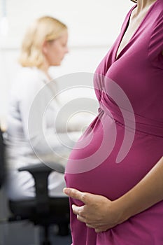 Pregnant woman at work holding belly with coworker photo