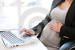 Pregnant woman working on laptop.