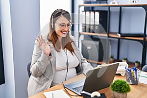 Pregnant woman working at the office wearing operator headset looking positive and happy standing and smiling with a confident