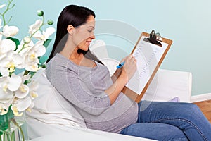 Pregnant woman writing baby names