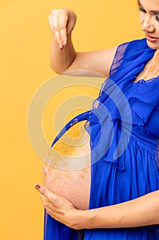 Pregnant woman on yellow background with big tummy, waiting for baby.