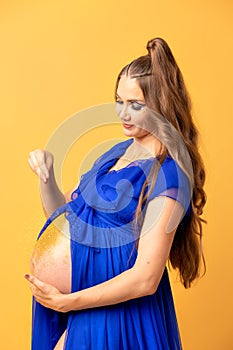 Pregnant woman on yellow background with big tummy, waiting for baby.