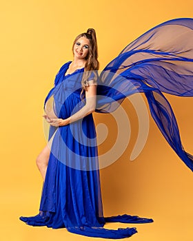 Pregnant woman on yellow background with big tummy, waiting for baby