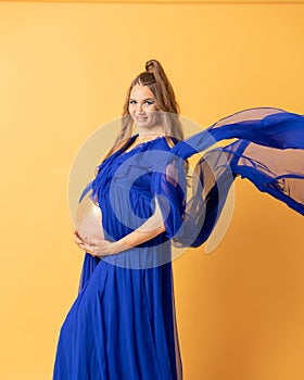 Pregnant woman on yellow background with big tummy, waiting for baby.