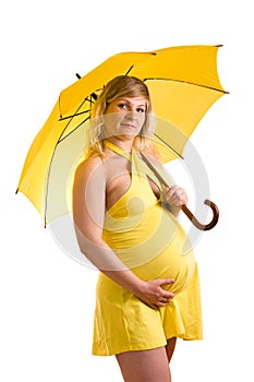 Pregnant woman in yellow dress with umbrella.