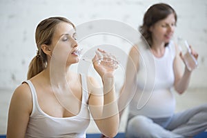 Pregnant women drinking water in fitness class