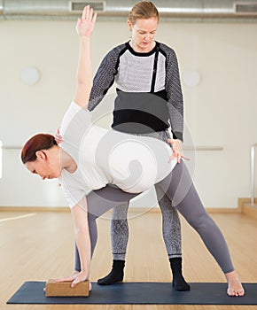 Pregnant woman practices yoga with an instructor. Extended Side Angle Pose or Parivrtta Parsvakonasana