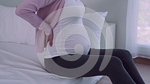 Pregnant women gently pat stomach with hands. Pregnant women are feeling uncomfortable and have back pain due to weight gain as a