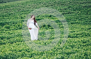 Pregnant women in green field in white dress