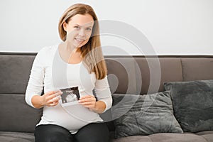 Pregnant women holding echo pictures in hand