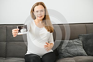 Pregnant women holding echo pictures in hand