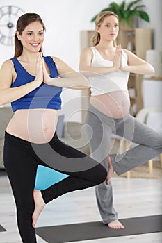 pregnant women meditates indoor in yoga pose