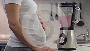 Pregnant women preparing a milkshake using a brand in the kitchen