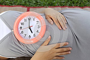 Pregnant women show clock on her belly to tell the time.