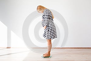 Pregnant woman standing on scales to control weight gain