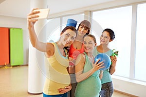 Pregnant women taking selfie by smartphone in gym