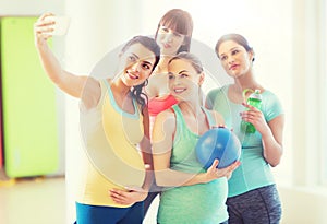 Pregnant women taking selfie by smartphone in gym