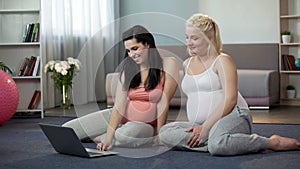 Pregnant women viewing websites on laptop, online shopping for future moms photo