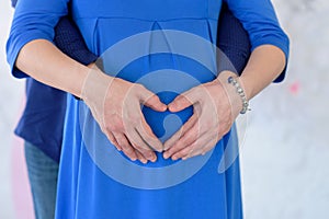 Pregnant wooman, hands of parents like a heart