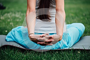 Pregnant yoga in the lotus position on the forest background. in the park the grass mat, outdoor, health woman.