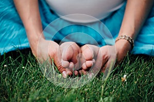 Pregnant yoga in the lotus position. in the park on the grass, doing exercises, stretching, outdoor, . feet close-up