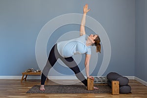 Pregnant yoga model working out indoo doing Extended Triangle pose