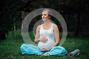 Pregnant yoga woman with mat portrait in park on the grass, breathing, stretching, statics. outdoor, forest.